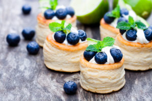 Bite-sized pastries are shown with blueberries on top.