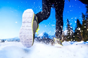 A runner wears waterproof running shoes as he runs outside in the snow.