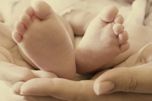 Tiny baby feet are shown being held by a pair of hands.