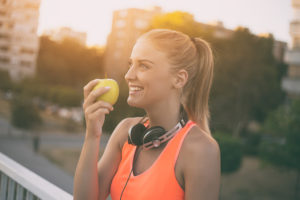 A woman in sports gear eats an apple.