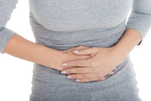 A woman holds their stomach and appears uncomfortable.