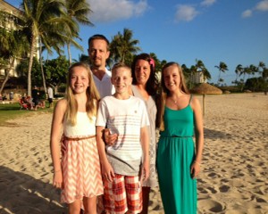 John, Lisa, Rachel, Andy and Hannah Cruden pose for a photo on the beach and smile.