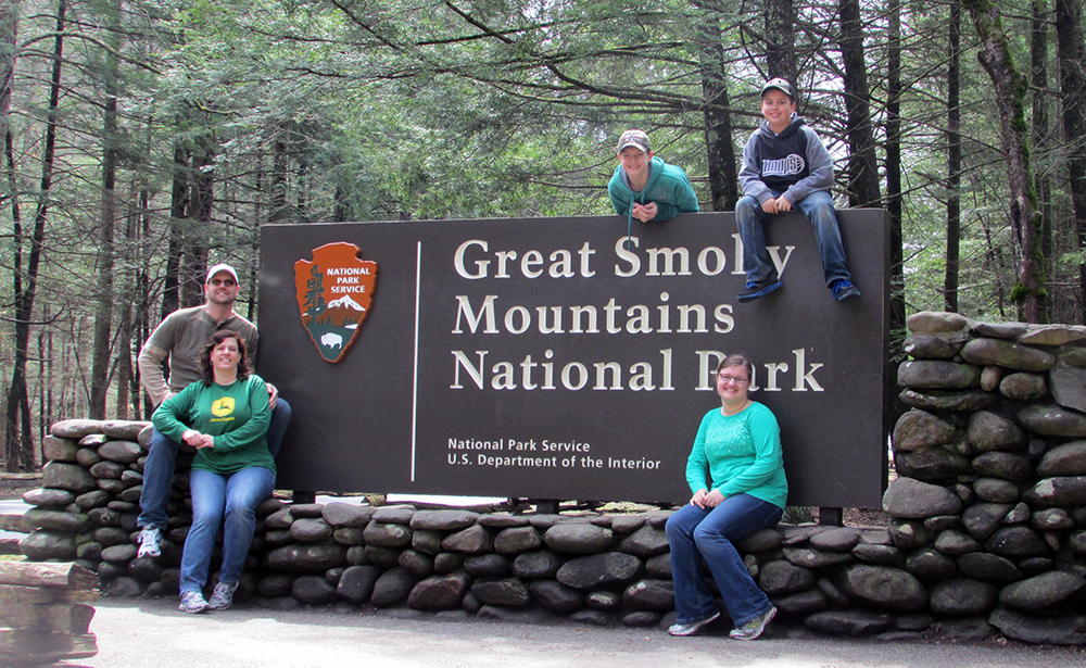 Mikaela Sterenberg poses for a photo with four family members in front of the "Great Smoky Mountains National Park" sign.