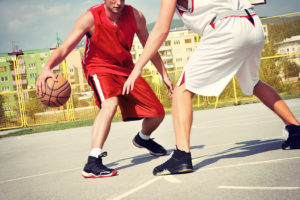 Two people play basketball outside. 
