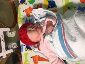 A baby, wearing a bright red hat, is shown asleep.