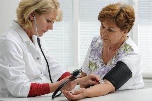 An elderly woman gets her blood pressure measured by a medical professional.