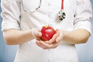 A medical professional holds an apple in their hands.