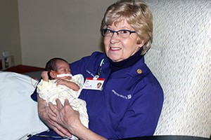 Pearl Tap rocks and soothes a baby as a volunteer at Spectrum Health Helen DeVos Children's Hospital.