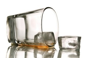 A glass lies on its' side with a little bit of alcohol in it.