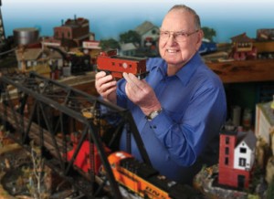  80-year-old Ron Avery poses for a photo with his train set.