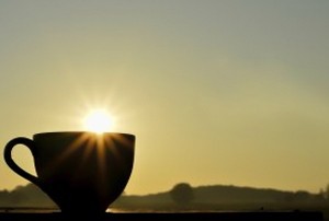 A cup lies on the ground outside, while a sun rises in the background.