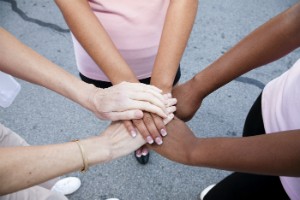 A group of people place their hands together in a huddle.