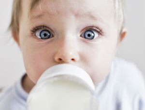 A baby drinks out of a baby bottle.