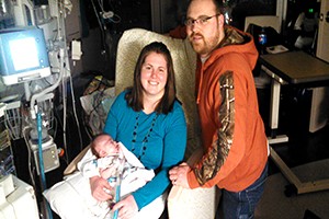 Amanda and Jeff Miles pose for a photo in the NICU with their 'littlest fighter.'