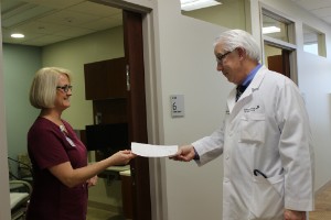 Dr. Julian Schink hands a medical professional some paperwork at Spectrum Health Medical Group's Gynecologic Oncology department in the Lemmen-Holton Cancer Pavilion.