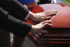 A few people place their hand on a casket.