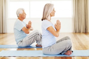 An elderly man and an elderly woman participate in meditation.