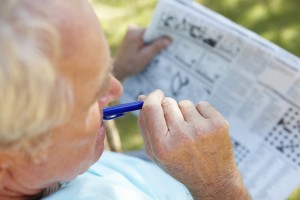 An elderly man looks at a newspaper.