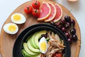 A salad with grapefruit, avacado, cherries, hard boiled eggs, and tomatoes shown.