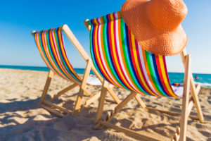 Two colorful chairs sit on the beach.