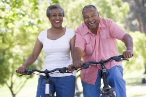 Two elderly adults ride bikes together.