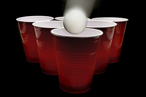A ping pong ball falls into a red cup during a game of beer pong.