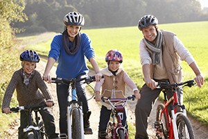 A family bikes together and wears helmets.