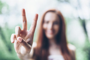 A woman holds up her hand and makes the 'peace sign' with her fingers.