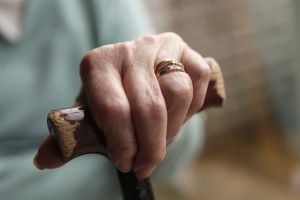 An elderly woman holds onto a cane for balance.