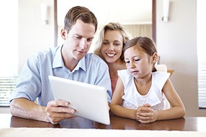 A father shows his daughter and wife his iPad.