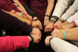 A group of people wear smart watches and put their hands together in a huddle.