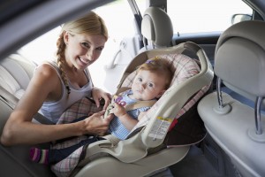 A mother buckles her toddler into a car seat.
