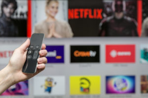 A person uses a remote to scroll through Netflix.