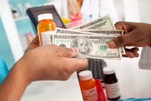 A person pays for their medication with cash at a pharmacy counter.