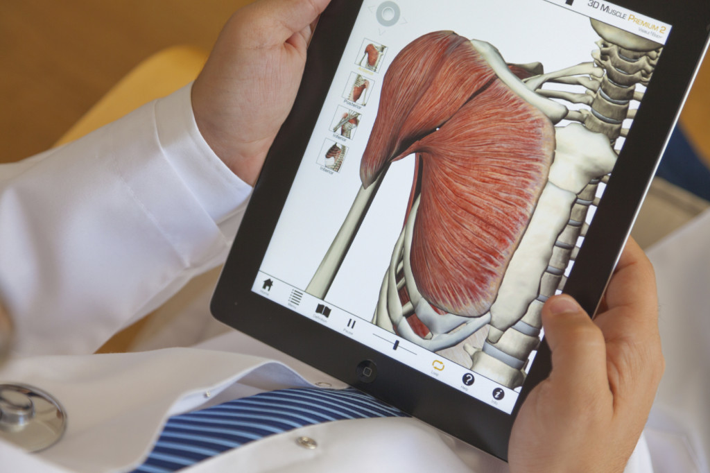 A doctor holds an iPad using a 3-D muscle application.