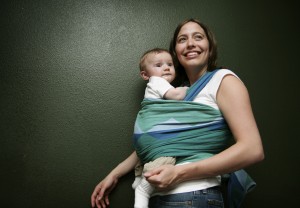 A mother holds a baby in a baby wrap.