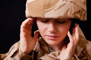 A military veteran is shown holding their head with discomfort.