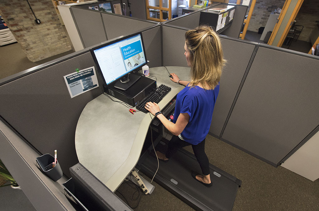Jessica Corwin, a Spectrum Health Community Nutricion Educator, is shown using the treadmill desk on her office floor.