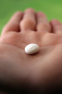 A hand holds a birth control pill.