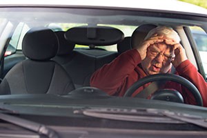 A man experiences road rage and holds his head as he drives.
