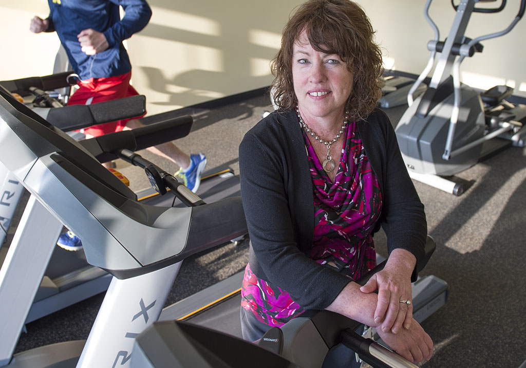 Spectrum Health Community Educator Kim Delafuente poses for a photo next to a treadmill.
