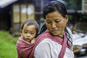 A woman holds onto her child with babywraping.
