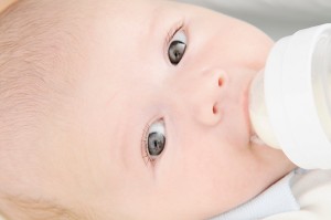 A baby drinks from a bottle of breast milk.