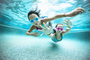 Two young girls hold their breath in a pool