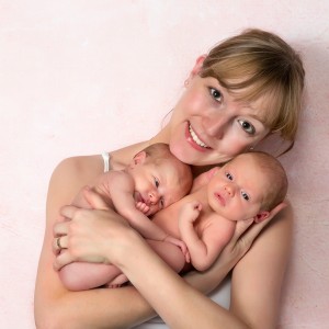 A mother holds two babies in her arms.