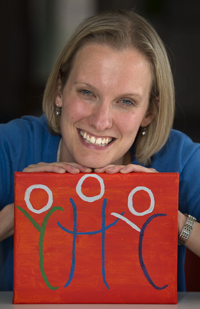 Amanda Winn is shown at the Children’s Healing Center with artwork of the center's logo that was painted on canvas by a visitor.