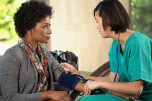 A woman gets her blood pressure measured by a medical professional.