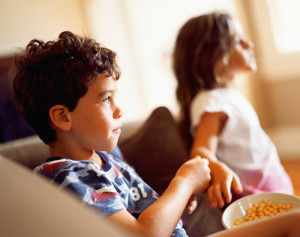 A young boy eats a few snacks while watching TV.