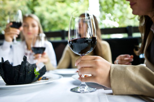A woman holds a glass of red wine before dinner.