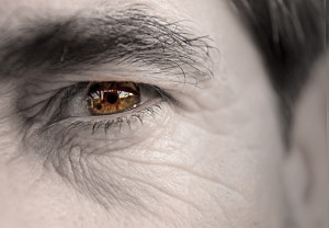 A man's eye is shown with many wrinkles under his eye.